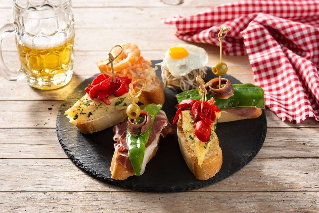 Tabla de pinchos y cerveza que ilustran el origen de las tapas españolas